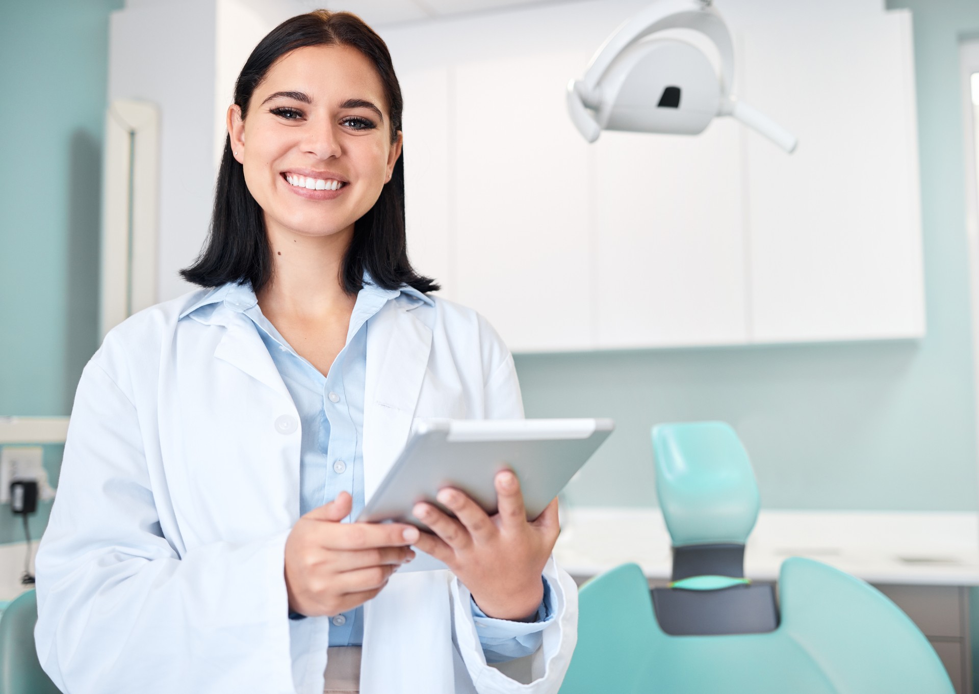 Happy, tablet and portrait of woman dentist with confidence in her office doing research at clinic. Smile, medical and young female orthodontist or dental doctor with digital technology in hospital.